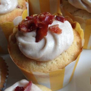 A maple bacon cupcake in a yellow and white liner
