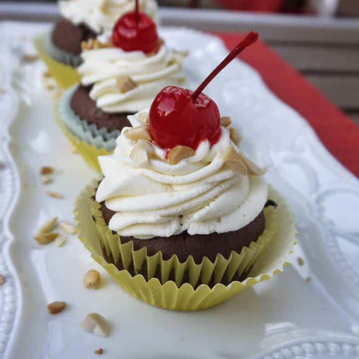 Chocolate cupcakes topped with fluffy white frosting and a cherry
