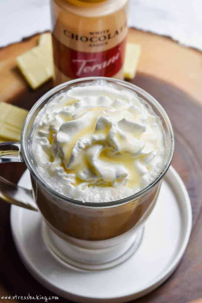 White chocolate mocha with whipped cream and white chocolate syrup in a clear mug