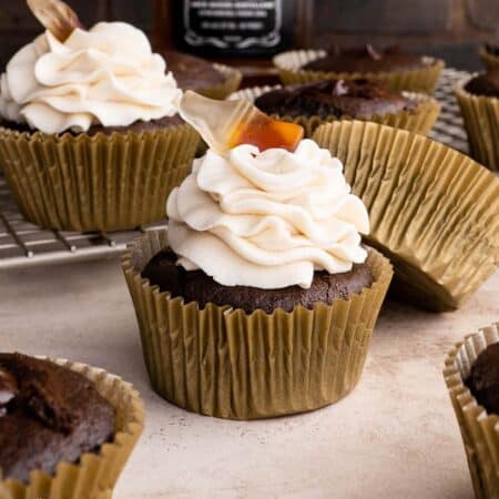 Chocolate whiskey cupcakes scattered around a light colored surface