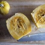 Yellow spaghetti squash sliced in half on a cutting board