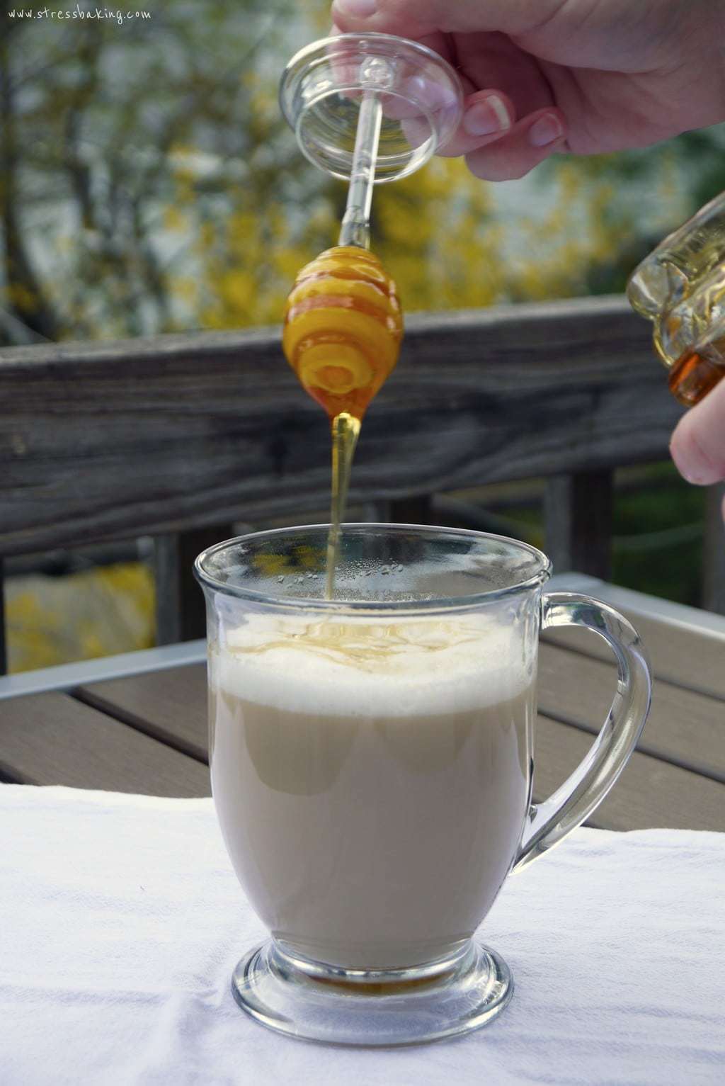 Honey being drizzle onto a latte in a clear mug