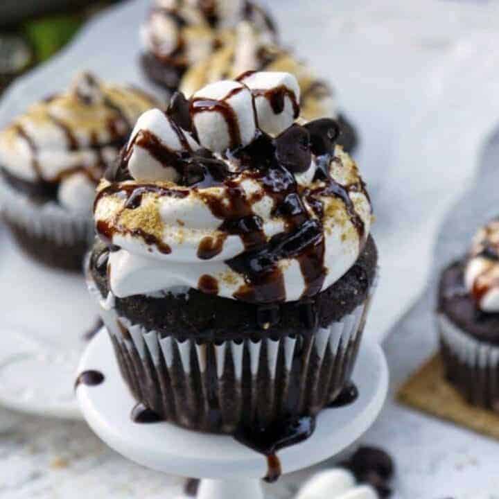 Chocolate cupcake topped with marshmallow frosting, mini marshmallows, crumbled graham crackers and chocolate syrup