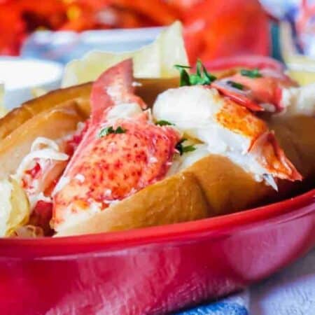 Lobster roll overflowing with claw meat in a red dish