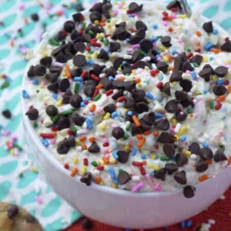 A white bowl full of cookie dough topped with mini chocolate chips and sprinkles