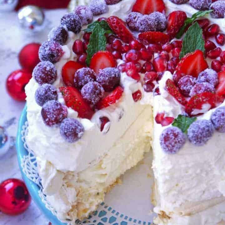 A layered pavlova with whipped cream and vibrant red berries