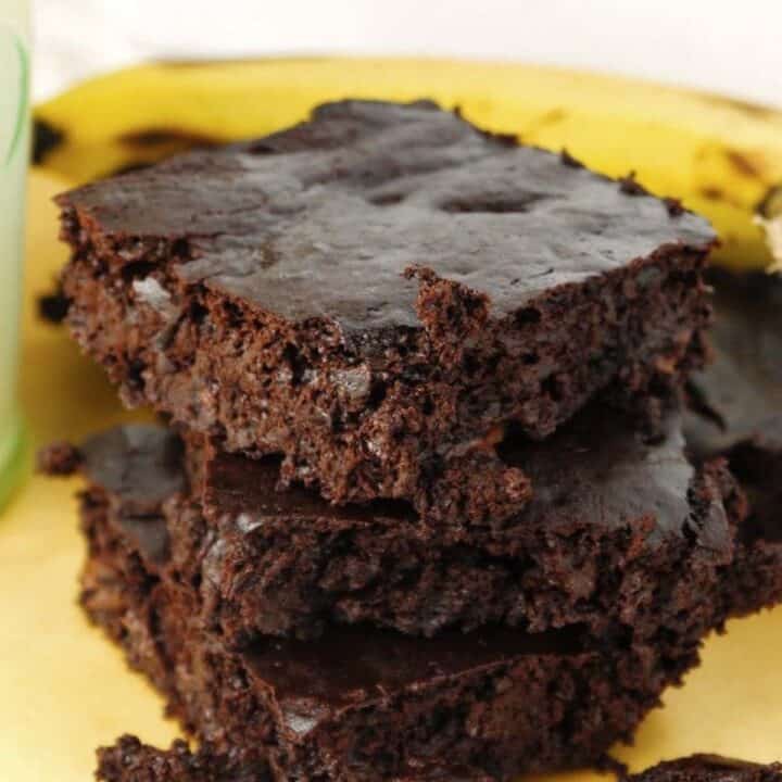 A stack of chocolate brownies in front of a stack of bananas