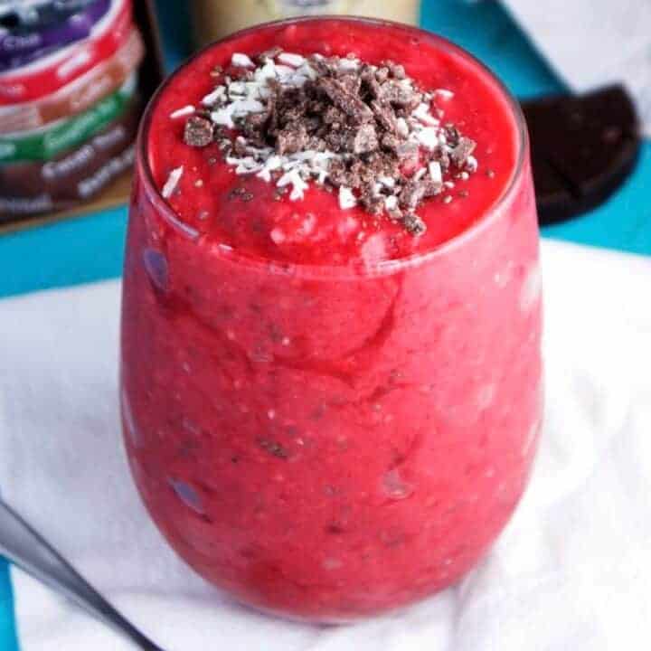 Brightly colored raspberry mango smoothie topped with shredded coconut and chocolate bits