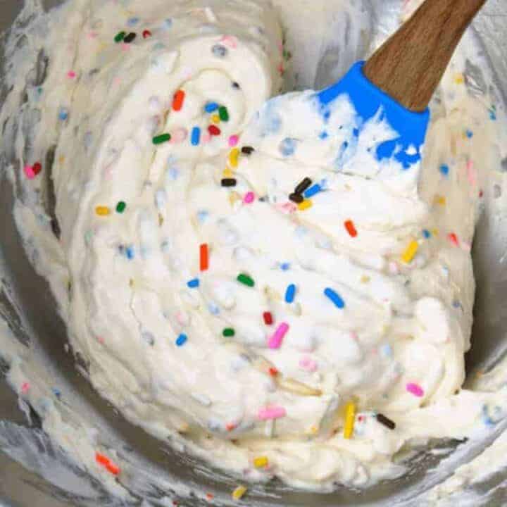 Fluffy whipped cream with sprinkles in a mixing bowl