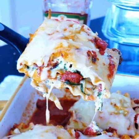 A slice of veggie lasagna being lifted out of a baking dish with melty cheese