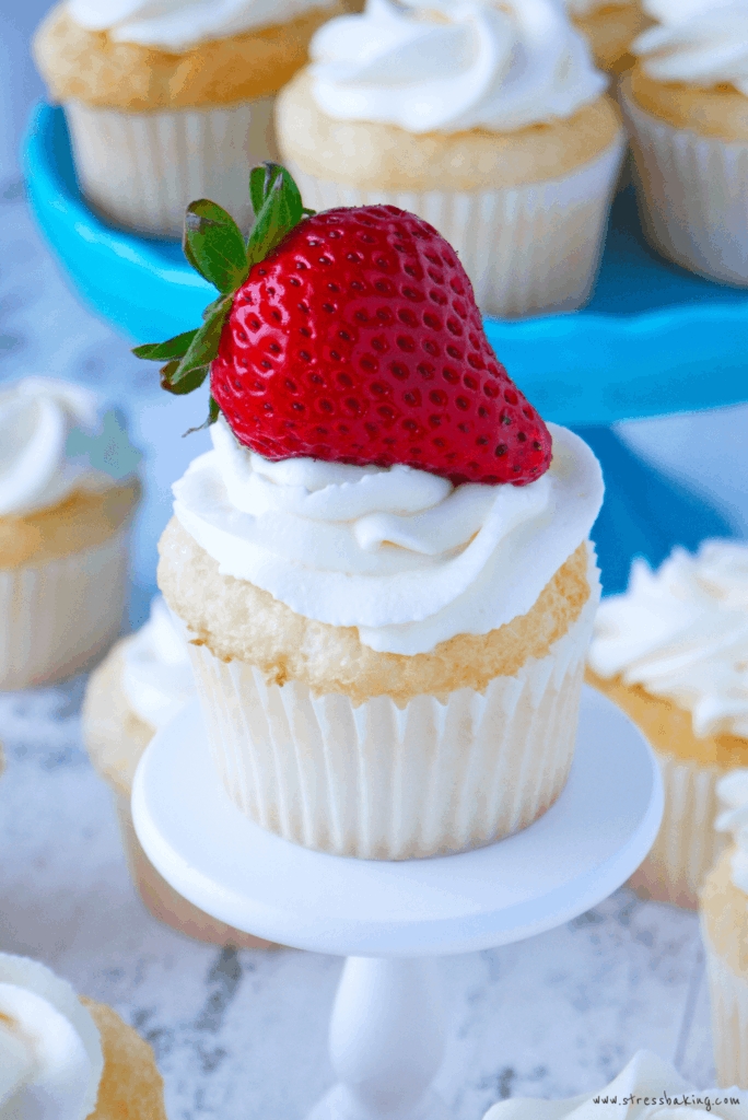 Super fluffy angel food cupcakes topped with light and boozy vodka mascarpone whipped cream and amaretto-soaked strawberries! | stressbaking.com