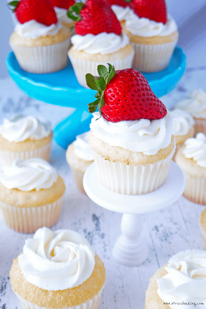 Super fluffy angel food cupcakes topped with light and boozy vodka mascarpone whipped cream and amaretto-soaked strawberries! | stressbaking.com