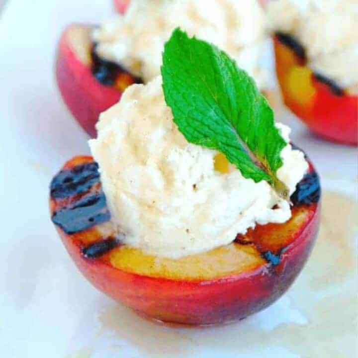 Grilled peaches topped with cinnamon whipped cream and fresh mint leaves
