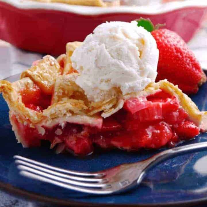 A slice of strawberry rhubarb pie topped with vanilla ice cream