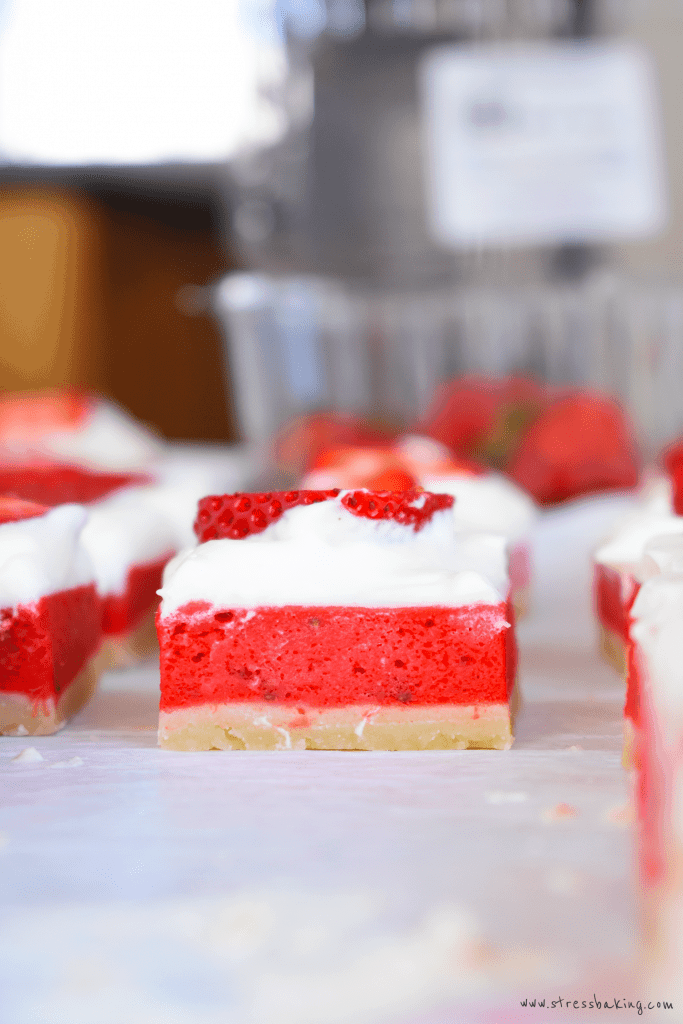 Side shot of strawberry rhubarb bars topped with mascarpone whipped cream
