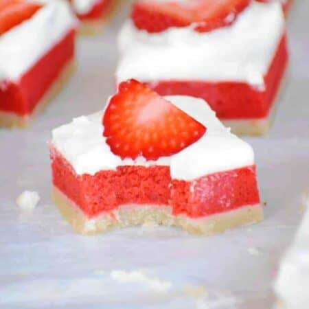 Red strawberry rhubarb filling sits between a lemon bars base and whipped cream topping