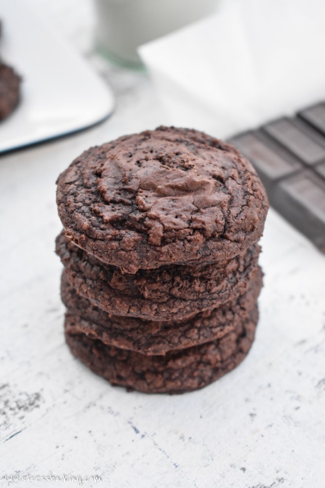 A stack of crinkled brownie cookies on a white surface