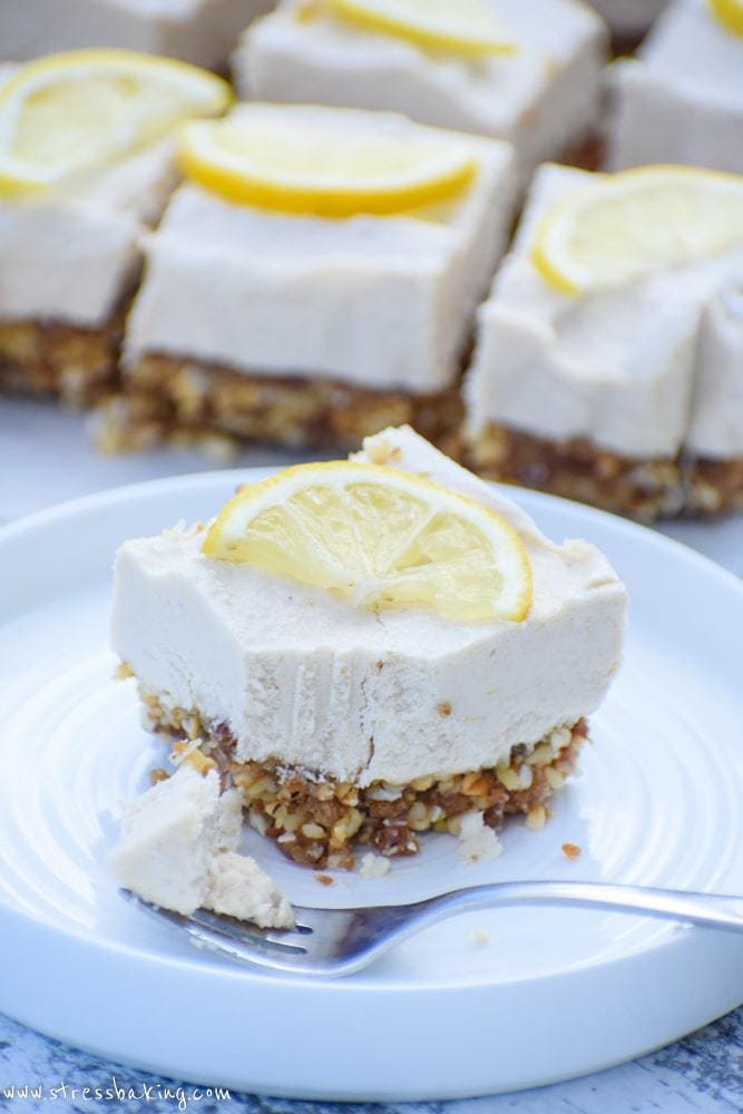 A slices of raw lemon cheesecake bars topped with thin lemon slice with a forkful removed
