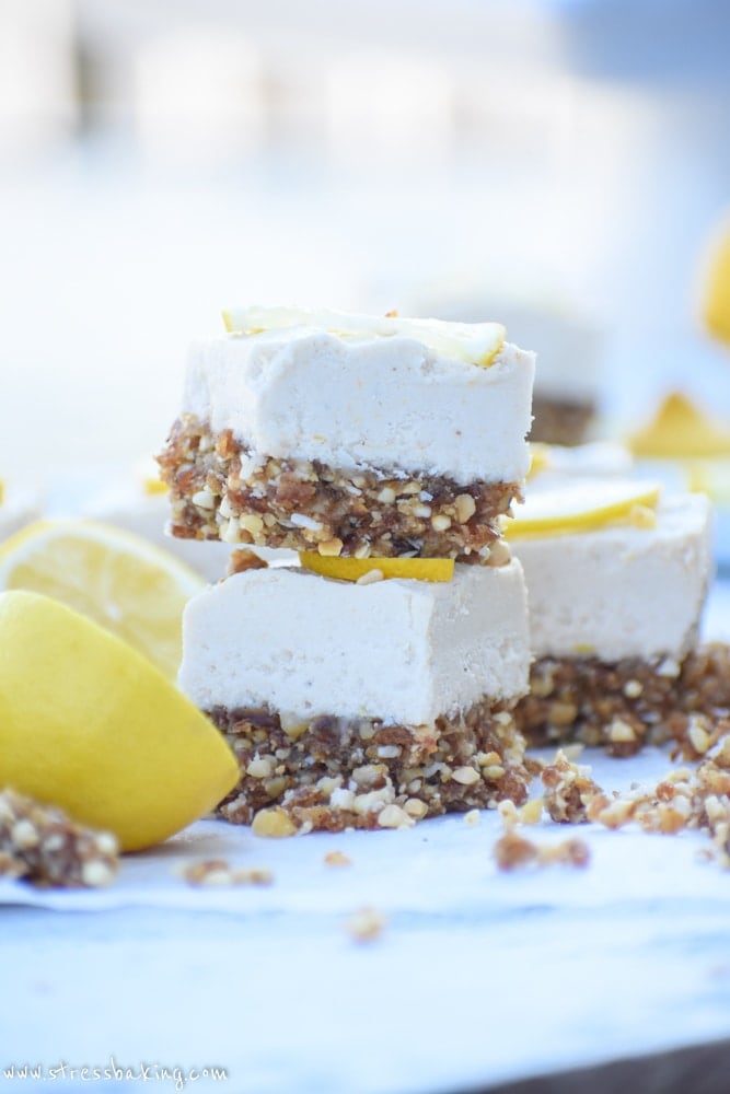 Stacked slices of raw lemon cheesecake bars topped with thin lemon slices