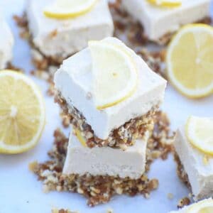 A stack of lemon cheesecake bars with a thin slice of lemon on top