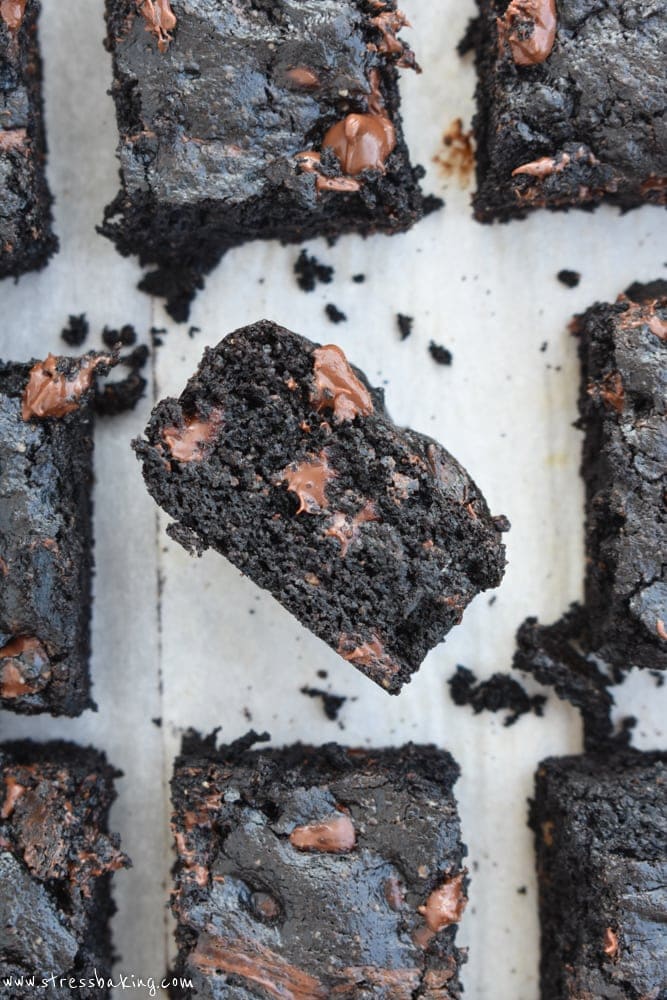 Thick, chocolatey brownies with melted chocolate chips and one on it's side showing the gooey center