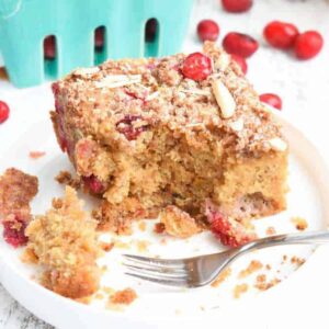 A square of moist cranberry coffee cake with fresh red cranberries