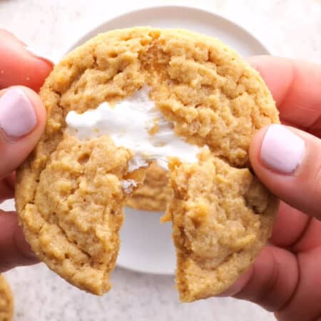 Peanut butter cookie being pulled apart to show gooey marshmallow fluff