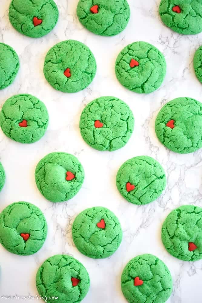 Overhead shot of vibrant green Grinch cookies decorated with little red heart sprinkles