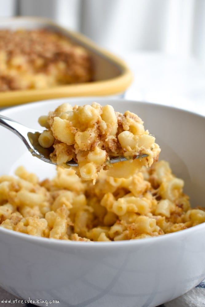 A forkful of macaroni and cheese above a white bowl