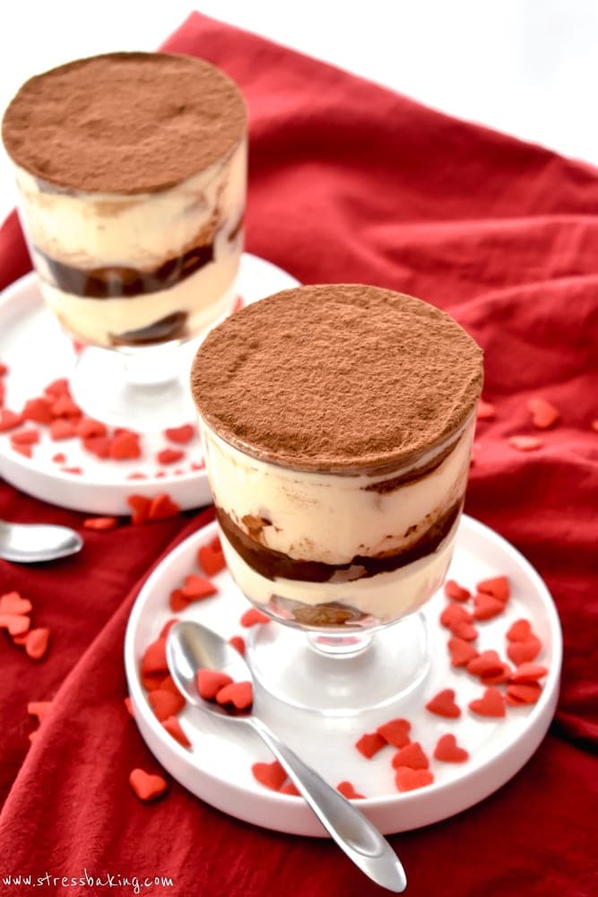 Two trifle dishes of tiramisu with a coating of cocoa powder on top and heart sprinkles