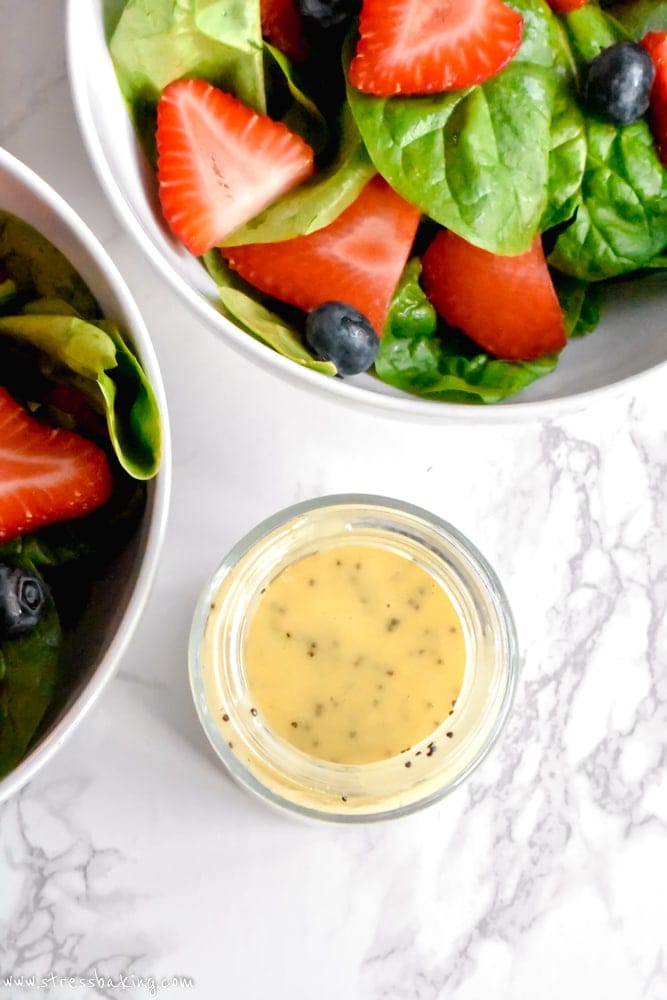 Lemon poppy seed dressing next to a strawberry spinach salad
