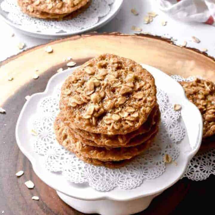 A stack of oatmeal lace cookies on a white platter