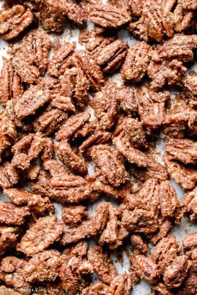 A close up of candied pecans piled onto parchment paper