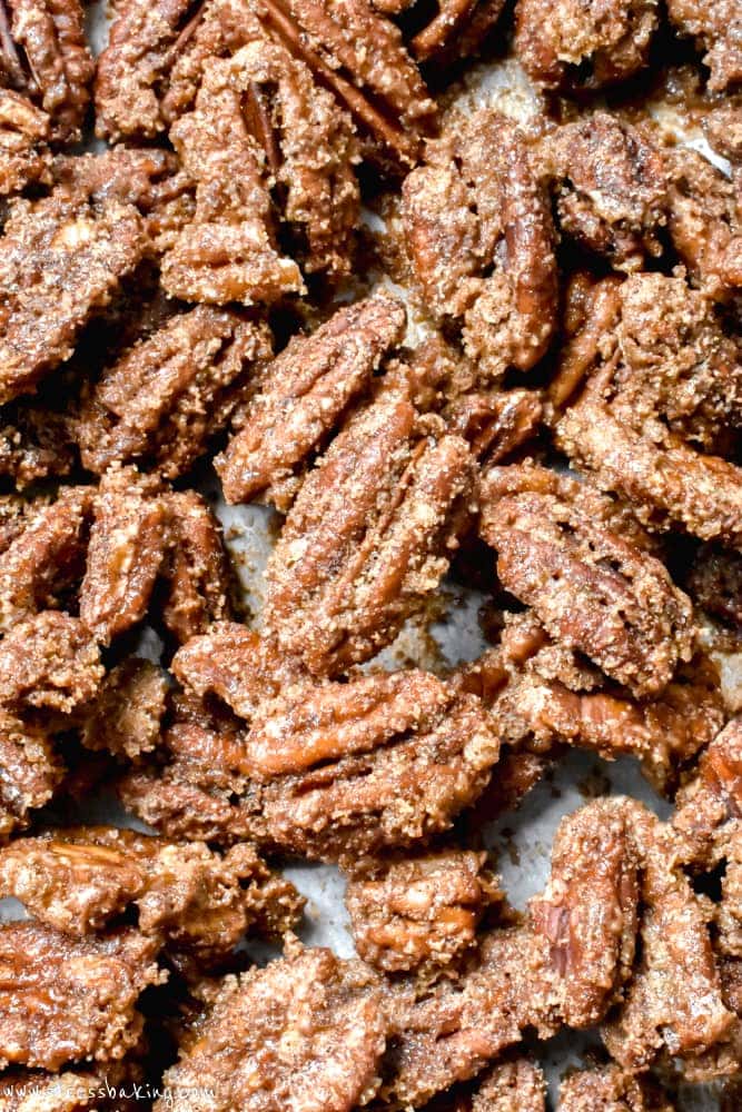 A close up of candied pecans piled onto parchment paper