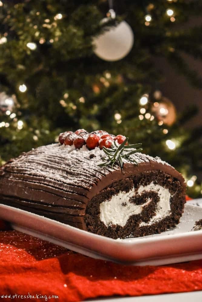 Yule Log Cake on a white platter with a slice on its side