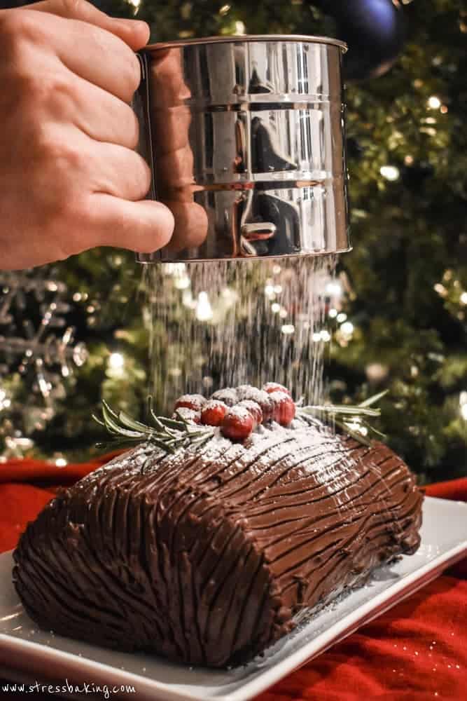 Yule Log Cake being dusted with powdered sugar