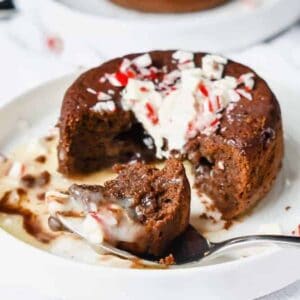 Chocolate lava cake topped with peppermint cut open with melted white chocolate spilling out