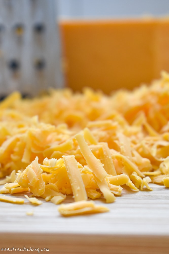 Shredded cheddar cheese on a wooden cutting board