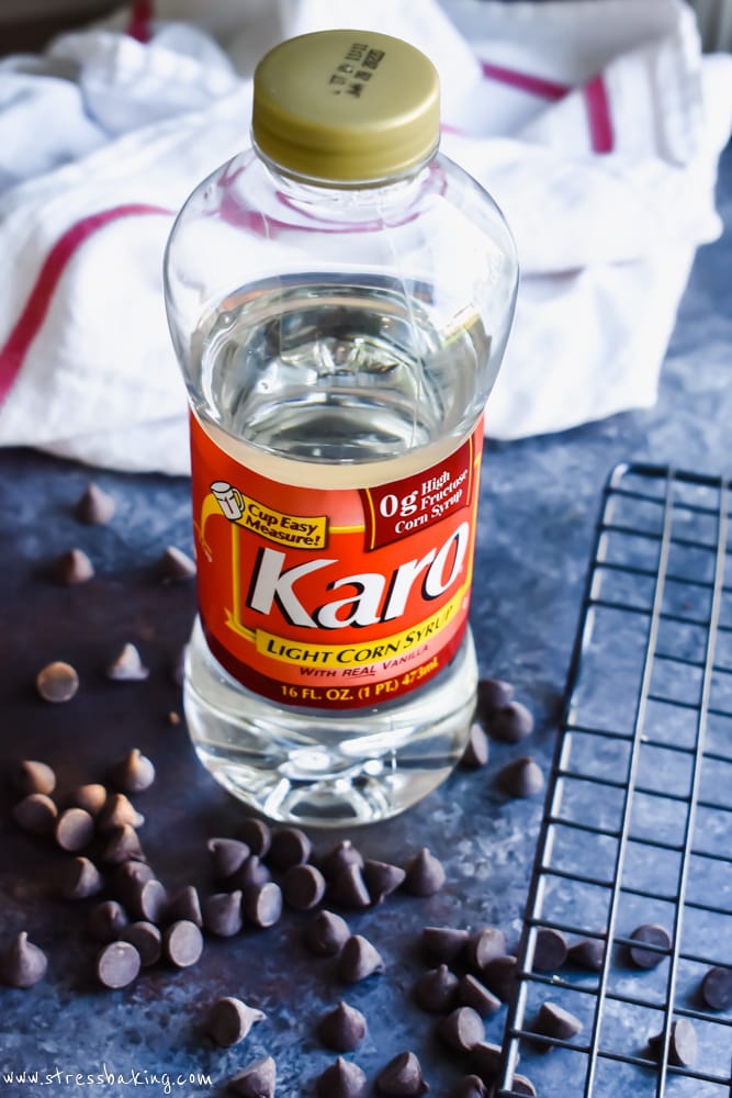 A bottle of Karo® Corn Syrup on a dark background surrounded by loose chocolate chips
