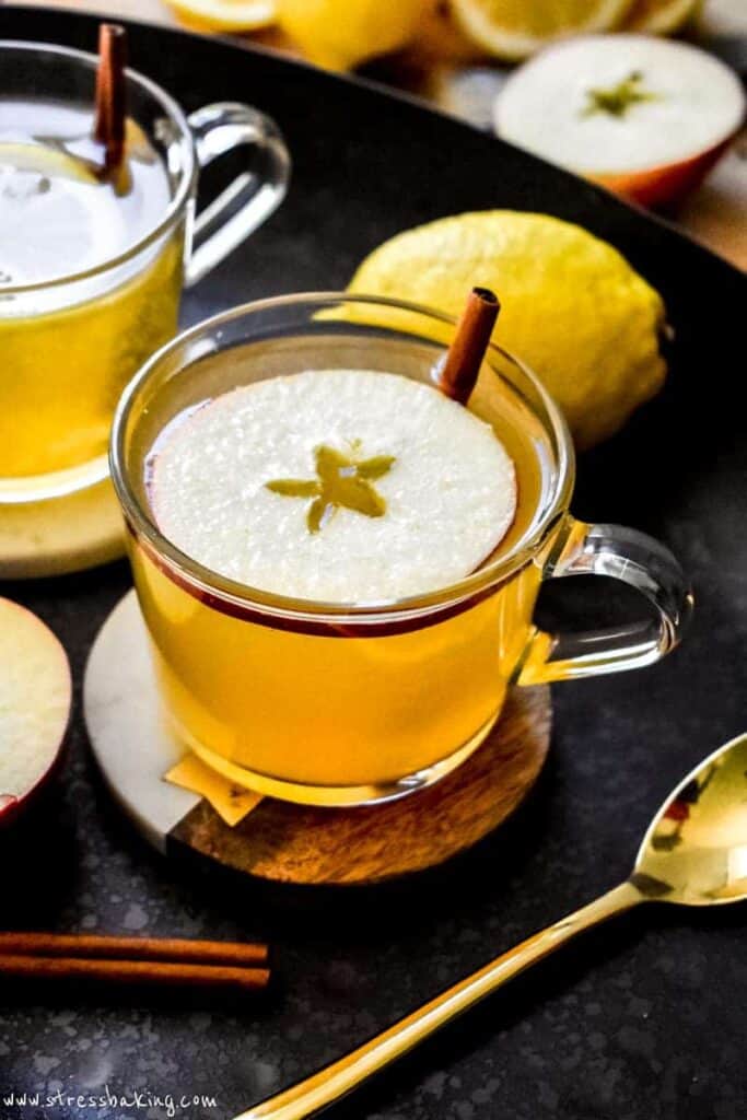 Hot toddy in a clear mug topped with apple slice