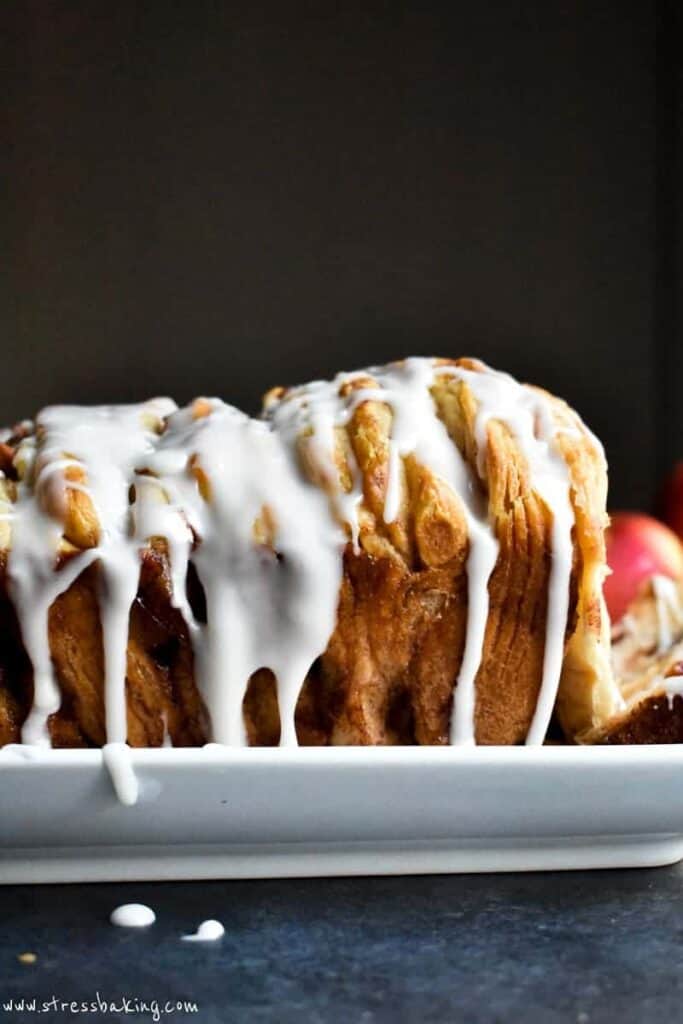Side shot of white icing dripping down the side of a golden brown loaf of monkey bread