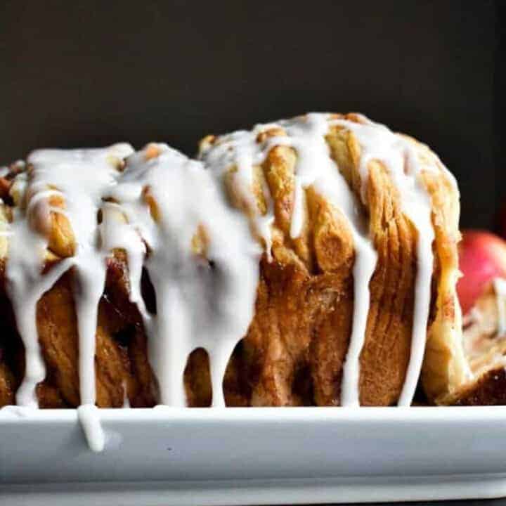 Side shot of white icing dripping down the side of a golden brown loaf of monkey bread