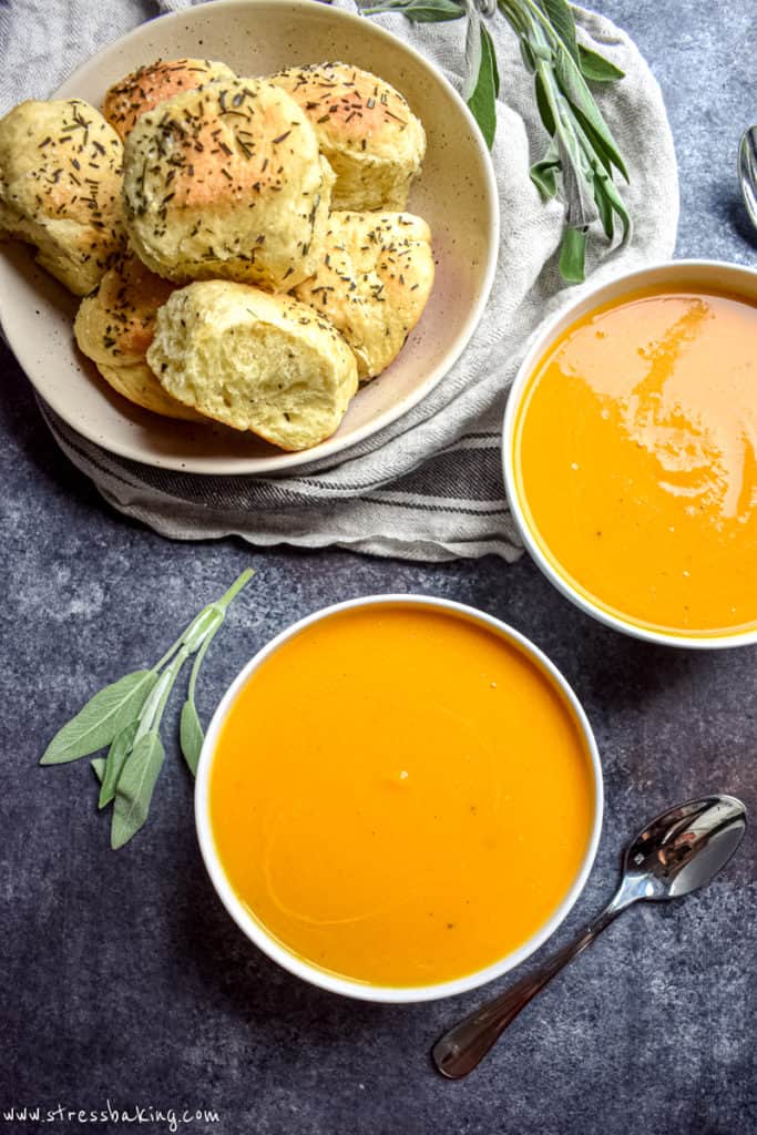 Overshot shot of two bowls of vibrant orange butternut squash soup in white bowls