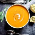 Overhead shot of vibrant orange butternut squash soup in a white bowl