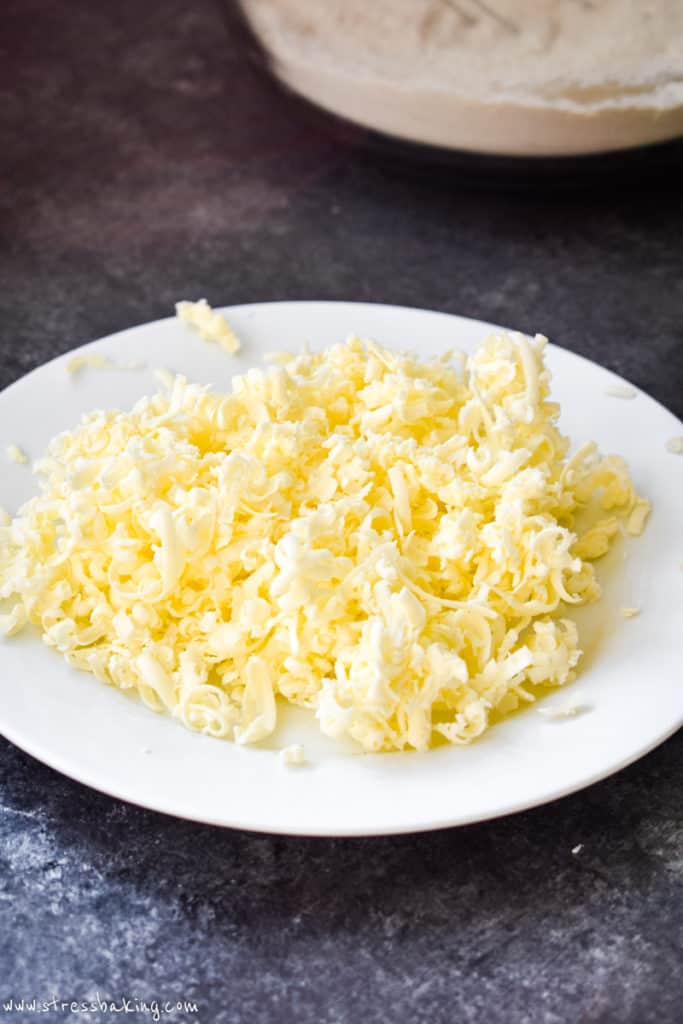 Yellow grated frozen butter curls on a white plate