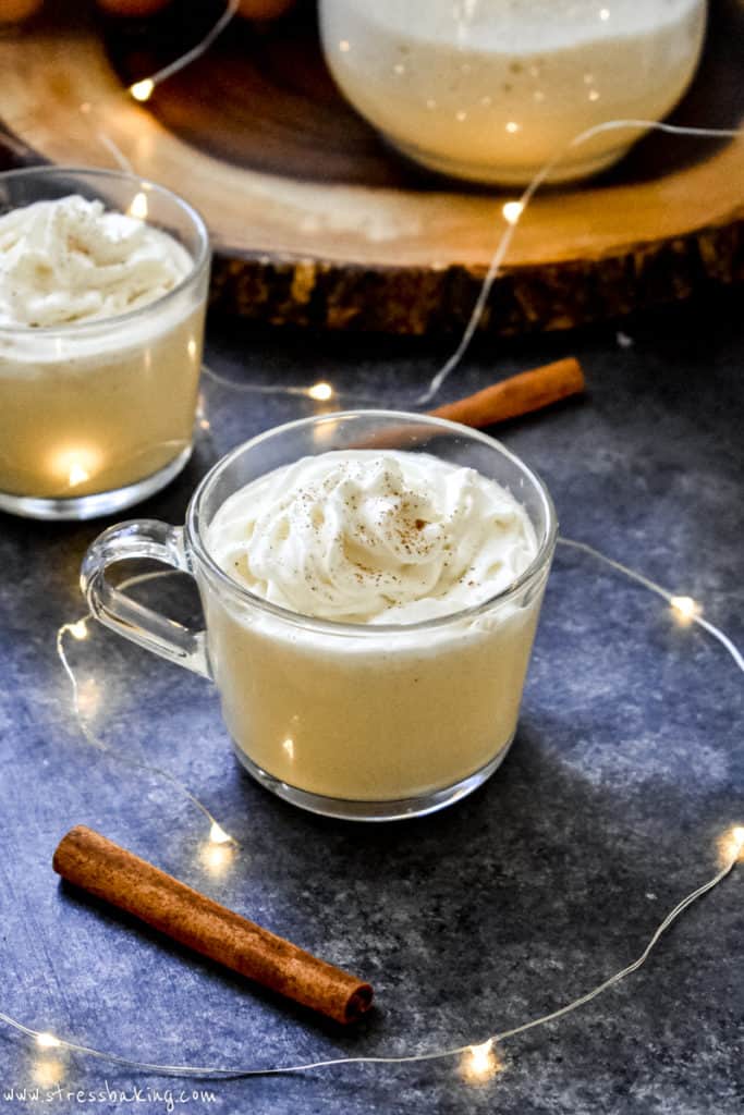 Two clear mug filled with creamy homemade eggnog and topped with whipped cream and nutmeg