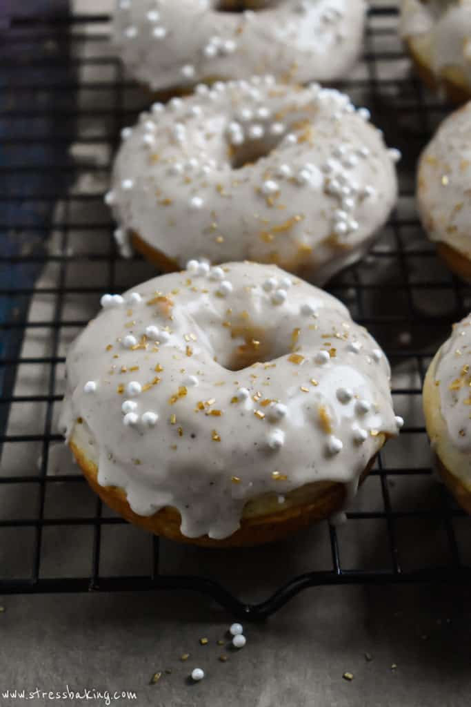 Eggnog donuts topped with a drippy glaze and gold and white sprinkles