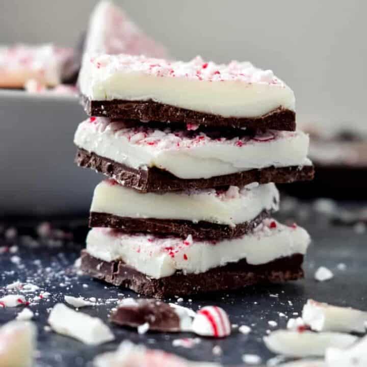 Four pieces of peppermint bark stacked on a dark counter