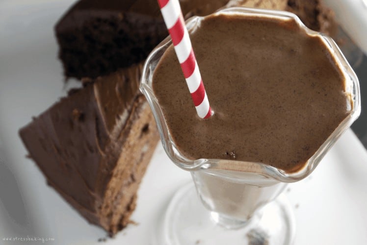 A chocolate cake shake with a red and white striped straw next to chocolate cake