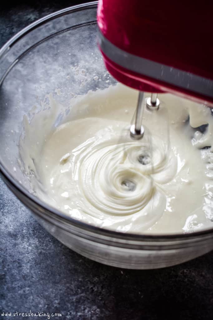 Whipping icing in a clear bowl with a hand mixer